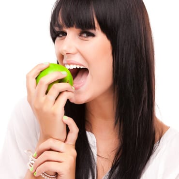 Young woman eating an green apple on isolated white background