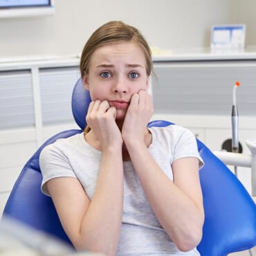 a girl sat in a chair, terrified that she had come for a tooth extraction